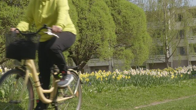Helsinki.Finland-May 26.2021: Beautiful shot of a middle aged lady riding a bicycle in Helsinki Finland. Awesome nature in the city.