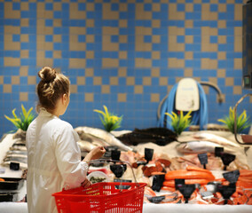 Woman shopping for fresh fish seafood in supermarket