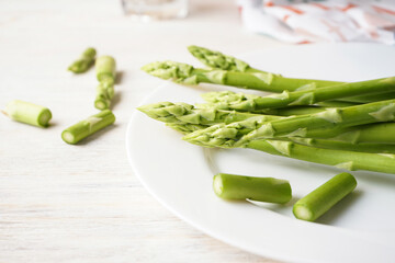 Fresh green asparagus in a plate on a wooden background, close-up.