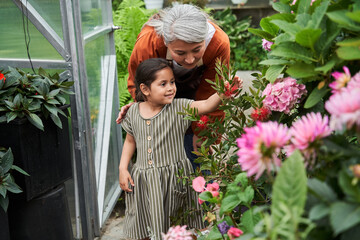 Girl reaching for a flower while walking through the garden
