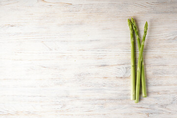 Fresh asparagus on wooden background, space for text. Flat lay.