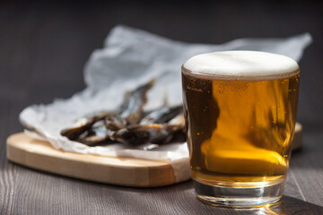 Close up. Beer in glass and dried salt fish in the wooden background.