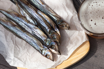 Close up. Beer in glass and dried salt fish in the wooden background.