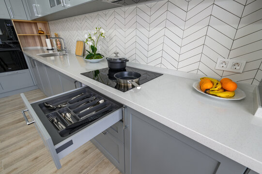 Trendy grey and white modern kitchen furniture with drawer pulled out
