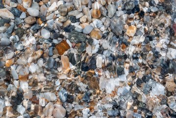 Moving Water over Small Colourful Stones Bottom Texture on Beach of Singitic Gulf in Aegean Sea - Water Lens Effect Background on Sithonia Chalkidiki Greece