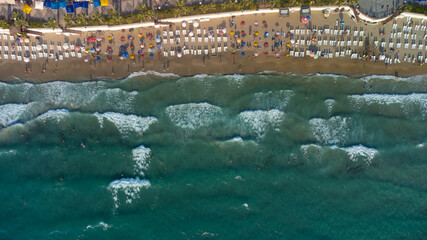 Aerial view from above Kusadasi coast beach aerial drone top view. People sunbathing. 