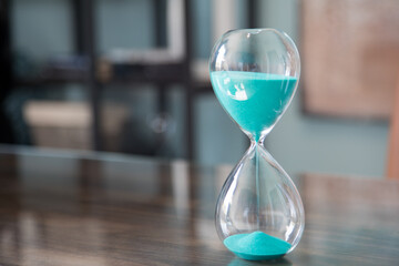 Glass sand timer with blue sand on desk