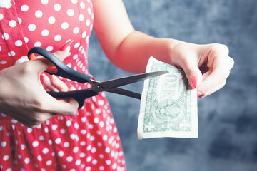 young woman cuts money with scissors