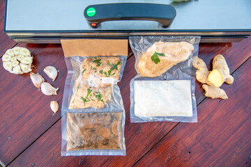 Sous vide cooking concept and low temperature cooking. Vacuum packed ingredients arranged on stained wooden background. Top view.Chicken and sauce