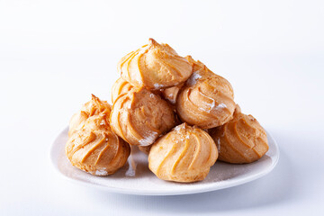 The profiteroles lie in a heap on a white plate.
