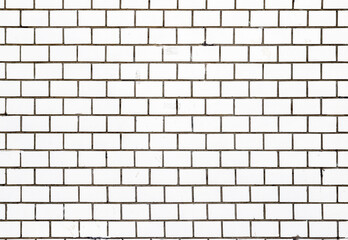 An old damaged wall made of white rectangular tiles as a background