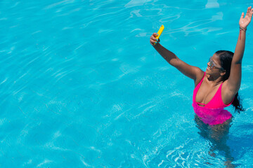 Woman taking a selfie with her cell phone in a swimming pool