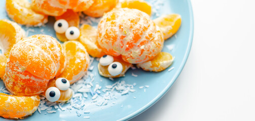 Fruit turtles, a snack made of fresh parts of mandarins served in the shape of water turtles on a blue plate