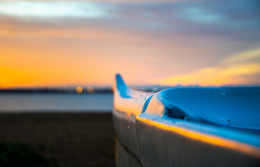 Hawaiian canoe on a beach at a beautiful sunrise. Yellow sky and the sea on background. Sunlight reflecting on the boat