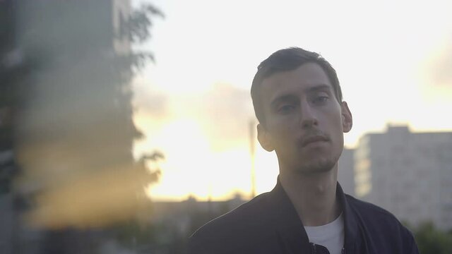 a thin young guy stands at sunset