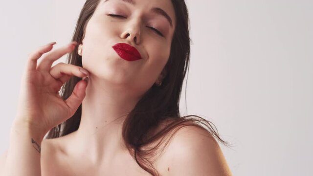 Female wellness. Beauty care. Spa therapy. Skincare cosmetology. Happy flirting smiling brunette woman with wet brown hair red lips makeup bare shoulders sending air kiss.