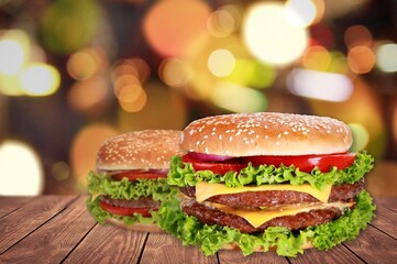 Tasty grilled homemade burgers with beef, tomato, cheese on rustic wooden background.