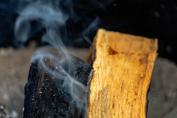 Photo of a mesquite dried-wood log emitting smoke and of a newly added kiln dried cooking wood in a...
