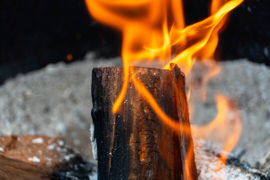 Photo of a mesquite dried-wood log in a fire pit set ablaze by fruit wood charcoal on a sunny day of June 20, 2021.