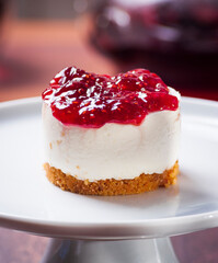 detail of a raspberry cheesecake on a white plate with blurred background