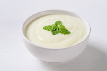 Yogurt in a bowl with mint leaf on white background, Healthy food