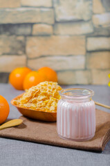 yogurt with natural glutem-free wheat cereal, with fresh orange fruits in a glass cup and a wooden bowl. with copyspace room for text. Greek