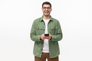 Young happy man laughing as he is looking at camera, holding his phone, isolated on gray background