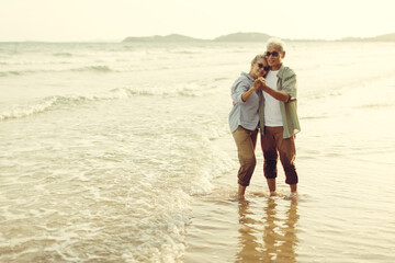 Retired couple dances happily in the evening sun by the sea. Plan life insurance and retirement concept.