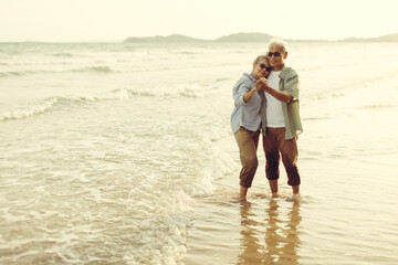 Retired couple dances happily in the evening sun by the sea. Plan life insurance and retirement...