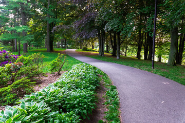 A footpath winds its way through a lush garden and forest during the late afternoon sun in...