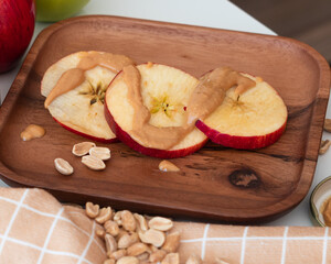 Apple slices with peanut butter on a wooden plate
