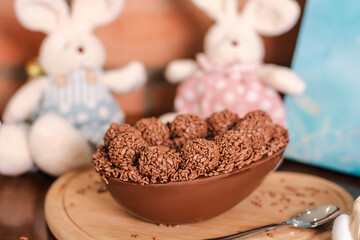 Brazilian Easter egg with a creamy spoon filled with Belgian chocolate brigadeiro flavor with Easter decoration in the background
