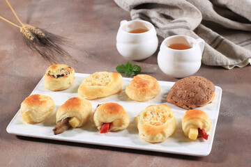 Assorted One Bites Mini Bread or Popular as Roti Unyil Venus on White Plate, White Background. Served for Accompanied Tea. Copy Space for Text