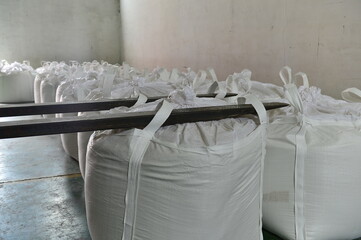 Many rows of plastic white sacks with goods are in big warehouse