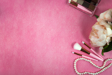 Womens cosmetics, handbag and makeup brushes lying on a pink background. Flat lay, top view.