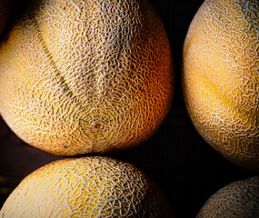 A close up of ripe cantaloupes with shadows around them.