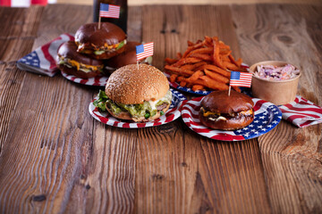 
Fourth of July celebration. American flag and decorations. Burgers on rustic wooden table.

