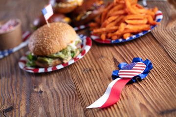 
Fourth of July celebration. American flag and decorations. Burgers on rustic wooden table.
