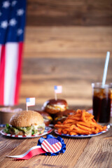 
Fourth of July celebration. American flag and decorations. Burgers on rustic wooden table.
