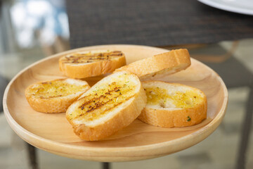 Selective focus shot of grilled garlic bread sliced with butter and spice looks delicious with yellow and brown color for snack or appetizer for yummy morning food or lunch served in restaurant.