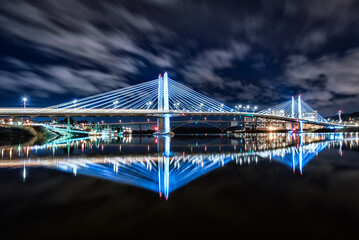 Long Exposure Night Photo of Portland, Oregon's Tilikum Crossing bridge reflecting in the Willamette River with moving clouds