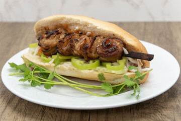 Hearty french bread sandwich loaded with pork belly skewer and jalapenos for a complete meal
