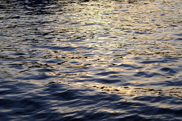 blue water wave with reflection of sunlight at sunset