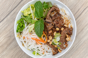 Overhead view of earty bowl of vermicelli noodles and seasoned beef with plenty of vegetables for a complete meal