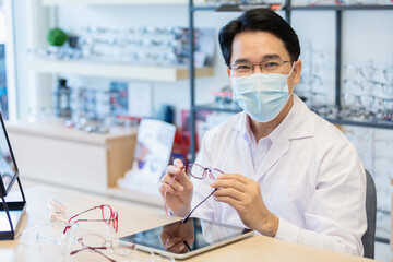 Man professional optician selling wear protective face mask sitting checking details quality of...