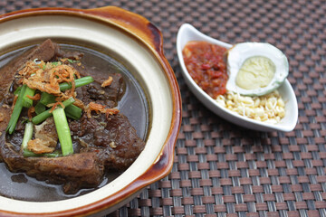 The black beef soup is an Indonesian traditional food served with buffalo meat and salted eggs, smeared with black sauce and very tasty