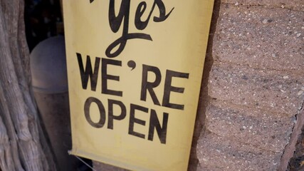 This video shows an old time styled business sign that reads "yes we're open".