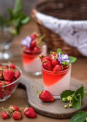 Creamy dessert with strawberry jelly in a glass with strawberry berry decor on a wooden background