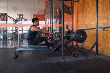 Latino man rowing on a crossfit machine inside a gym