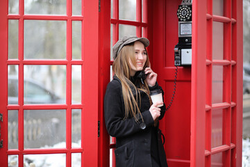 Beautiful young girl in a phone booth. The girl is talking on the phone from the payphone. English...